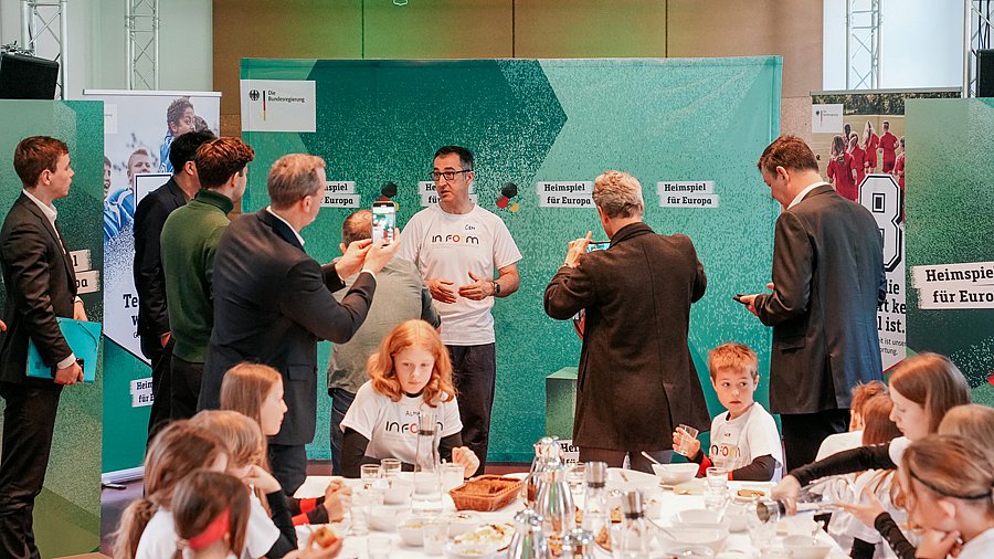 BM Özdemir im Gespräch, davor Kinder am Tisch