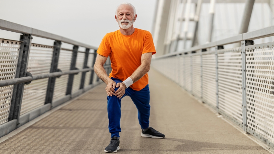 Älterer Mann bei Dehnübungen auf einer Brücke