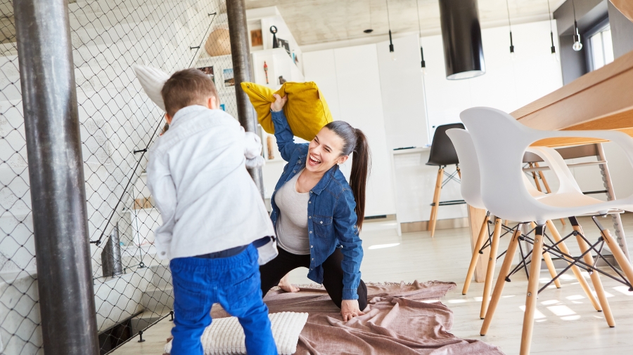 Muter und Kind machen eine Kissenschlacht in einer Wohnung