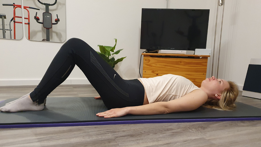 Junge Frau, entspannt auf dem Rücken liegend, Beine angestellt