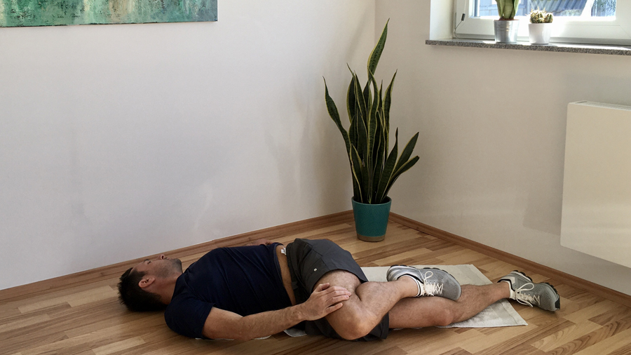 Mann, Rückenlage angewinkelte Beine nach rechts, Blickrichtung nach link