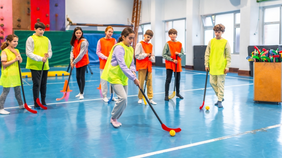 Kinder trainieren Hockey in einer Turnhalle