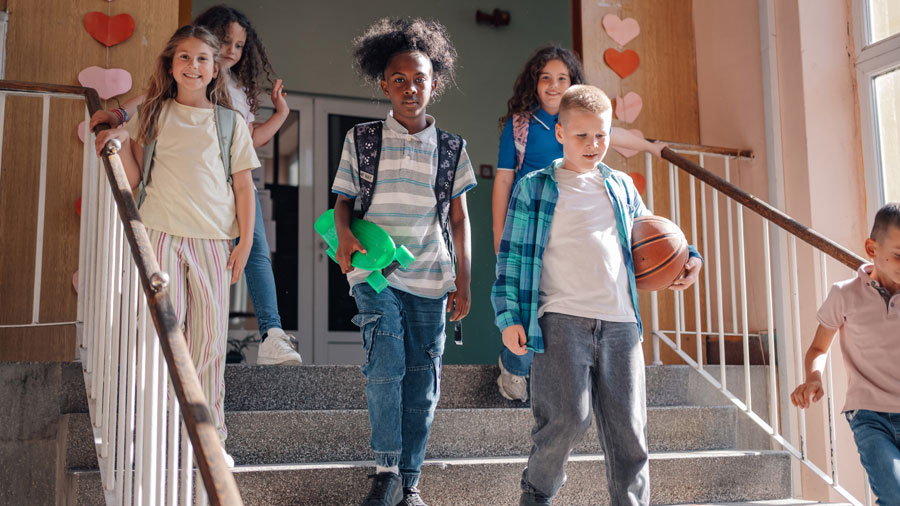 Schulkinder, die mit Sportsachen eine Treppe herunterkommen.
