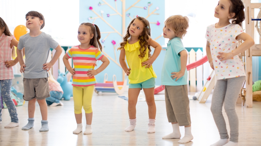 Kindergartenkinder stehen im Halbkreis und machen ein Bewegungsspiel