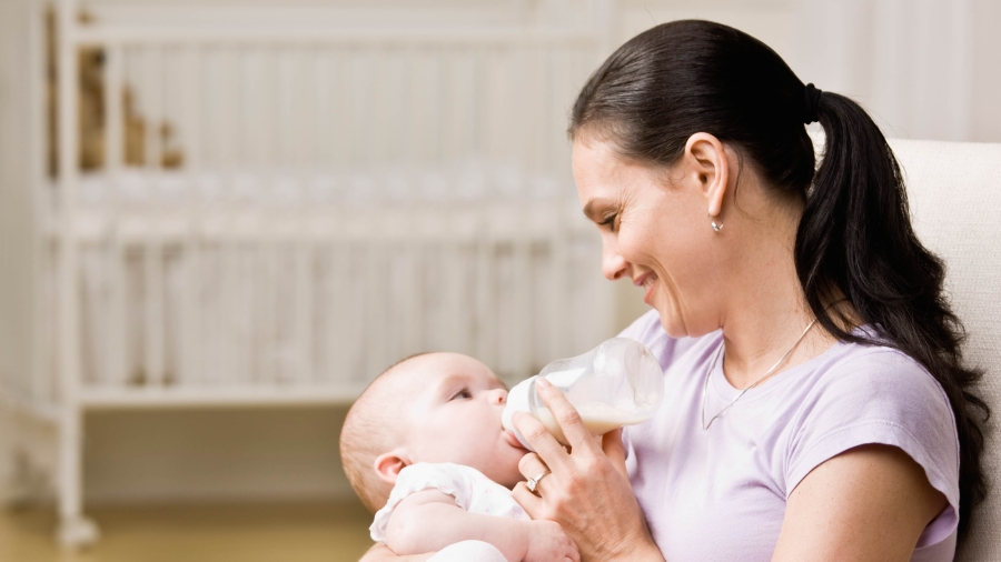 Frau füttert Baby mit einer Flasche