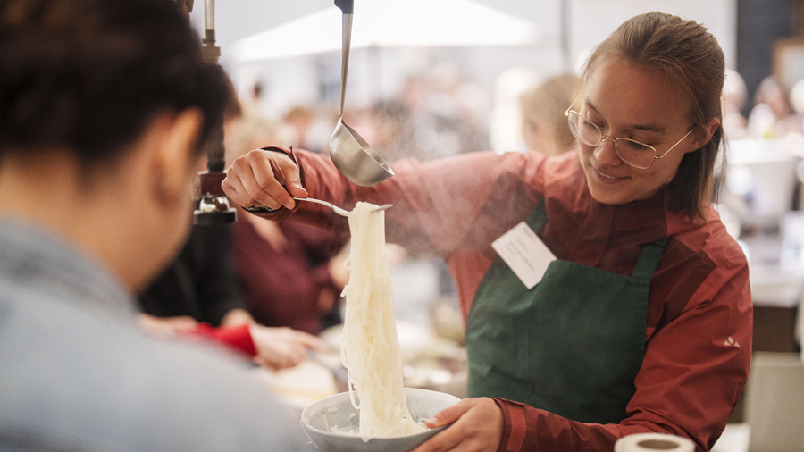 Junge Frau gibt Reisnudeln an einem Stand auf einen Teller