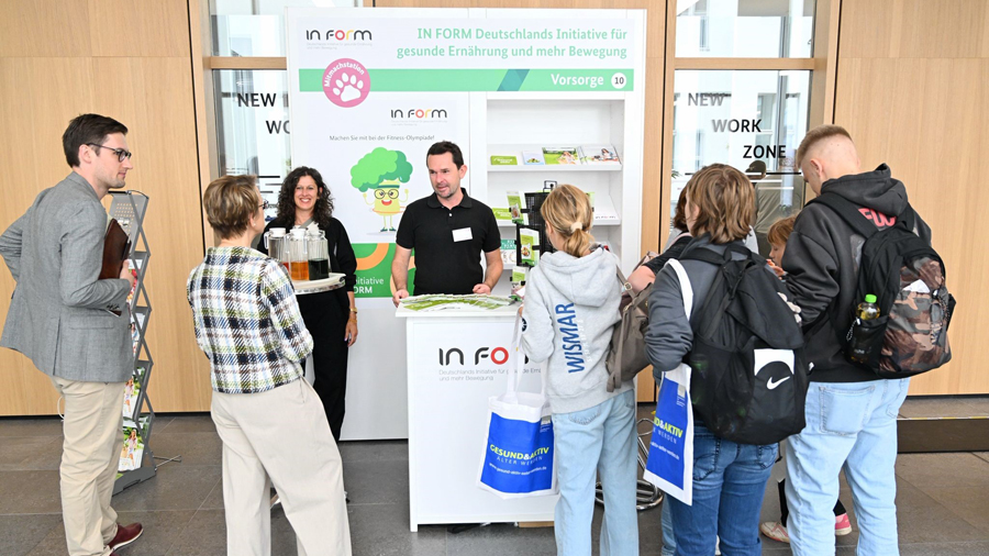 Mehrere Personen an einem Messestand der Initiative IN FORM