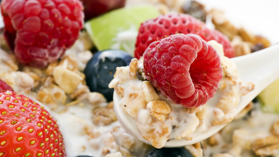 Löffel mit Müsil, Milch und Beeren
