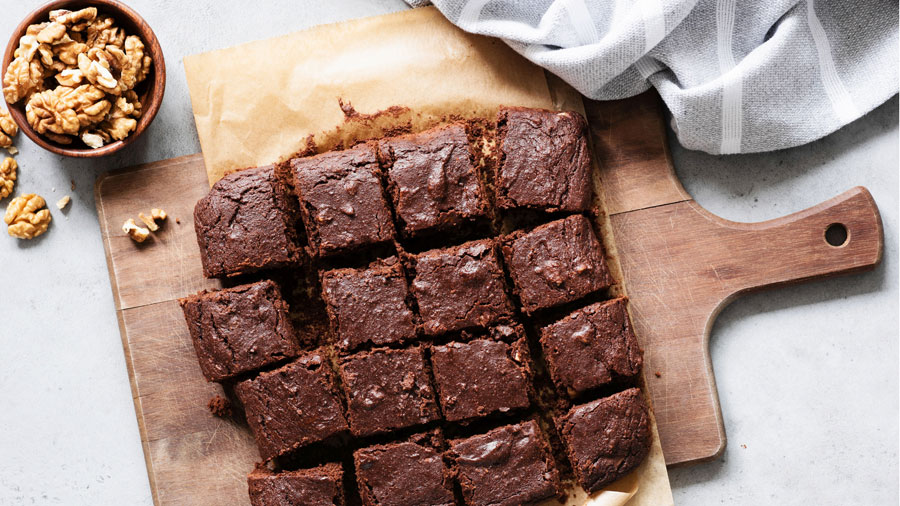 Brownies auf einem Holzbrett mit frishchen Walnüssen serviert.