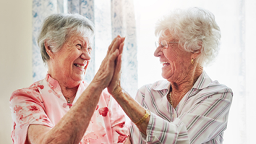 Zwei ältere Damen klatschen sich lachend ab
