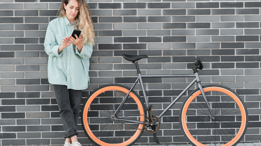 Frau mit Handy neben einem Fahrrad