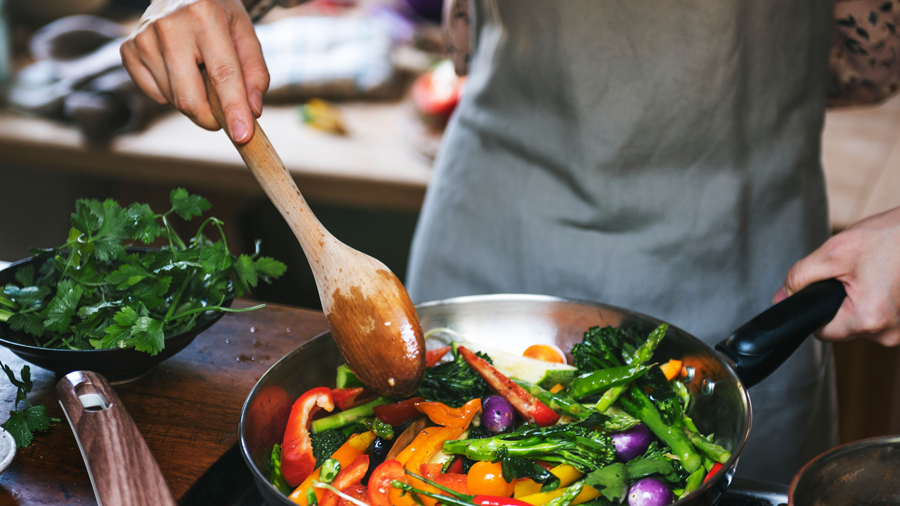 Hände rühren in einer Pfanne mit Gemüse
