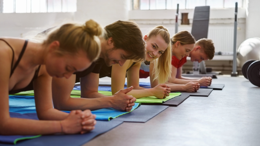 Gruppe junger Menschen auf Gymnastikmatten in einer Turnhalle
