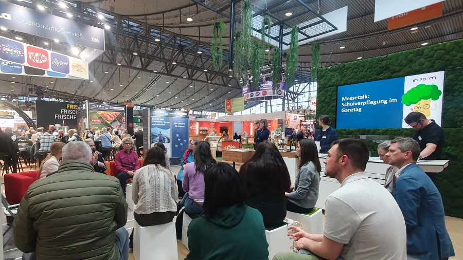 Messegäste auf dem Stand hören dem Talk zu