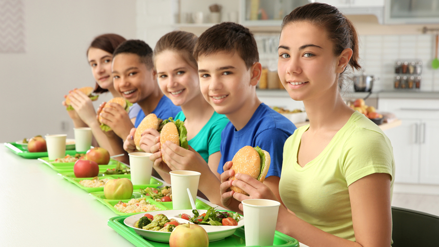 Fünf Jugendliche mit Esses-Tabletts vor sich sitzen in einer Reihe