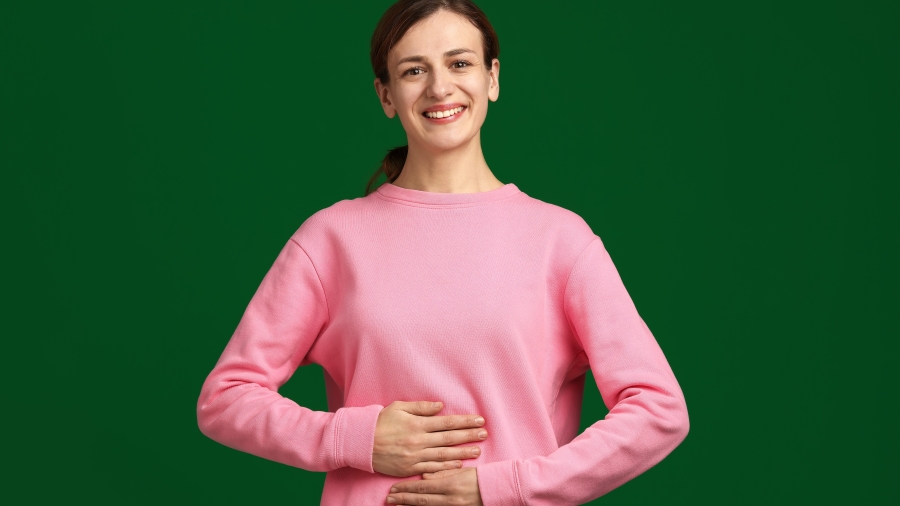 Lächelnde junge Frau, die sich den Bauch hält