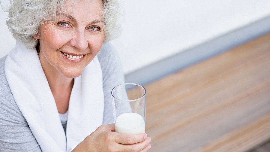 Frau mittleren Alters mit einem Glas Milch