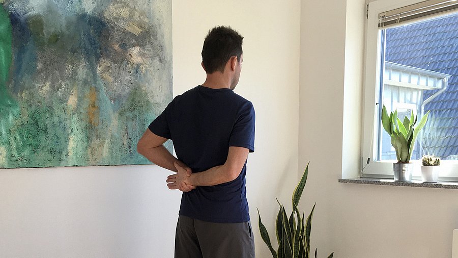 Mann, Arm hinter dem Rücken + Dehnübung