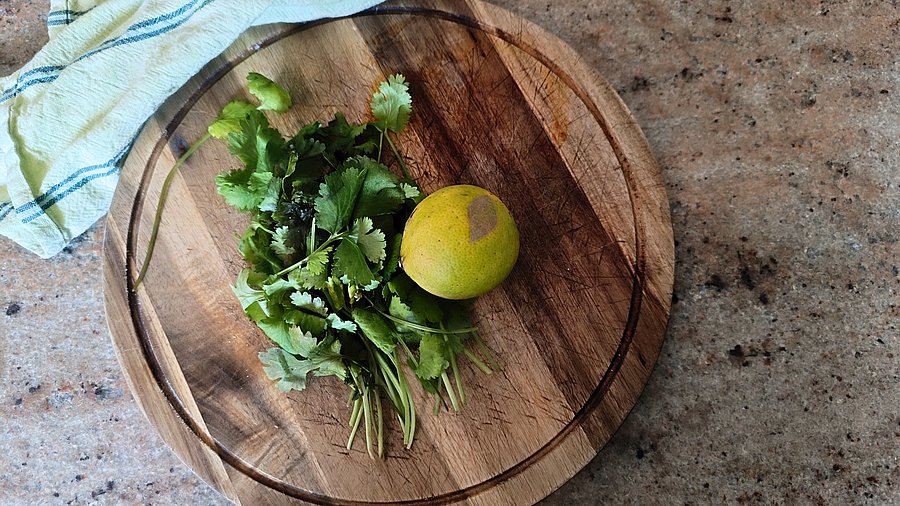 Limette und Koreander auf einem Holzbrett.