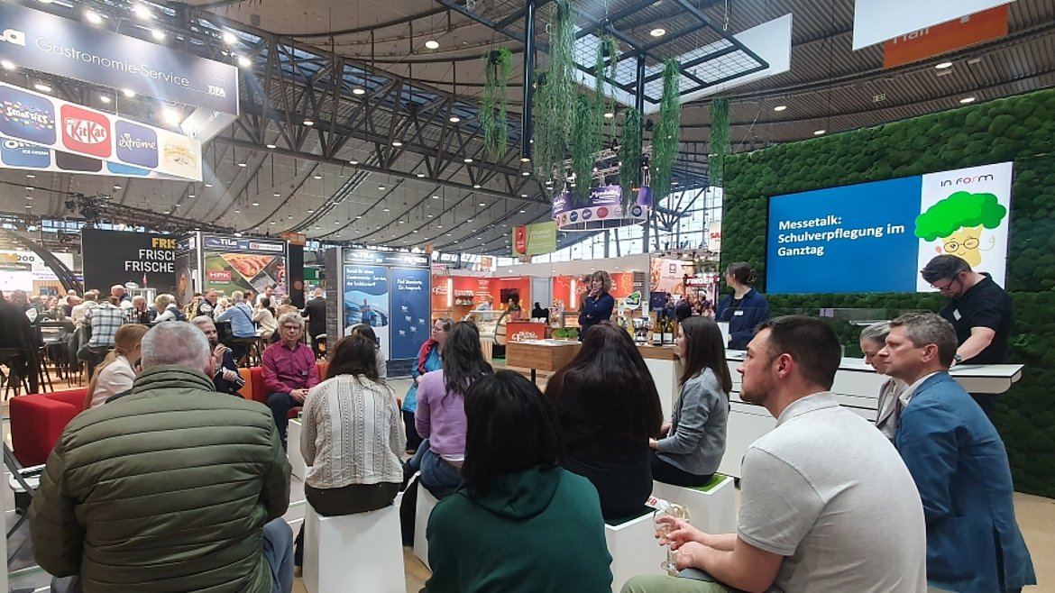 Messegäste auf dem Stand hören dem Talk zu