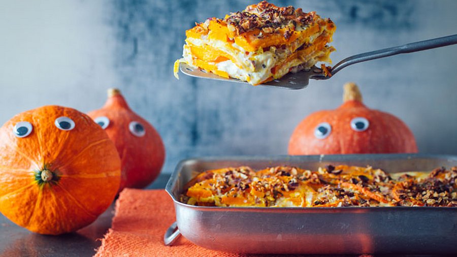 1 Blech Lasagne. 3 Kürbisse mit Gesichtern als Deko im Hintergrund.