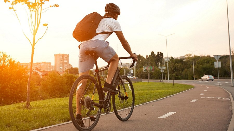 Ein Mann auf einem Rennrad steht auf einem Fahrradweg.