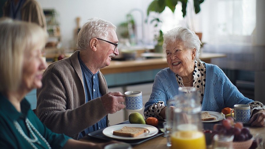 Senior und Seniorin beim gemeinsamen Essen an einem Tisch.