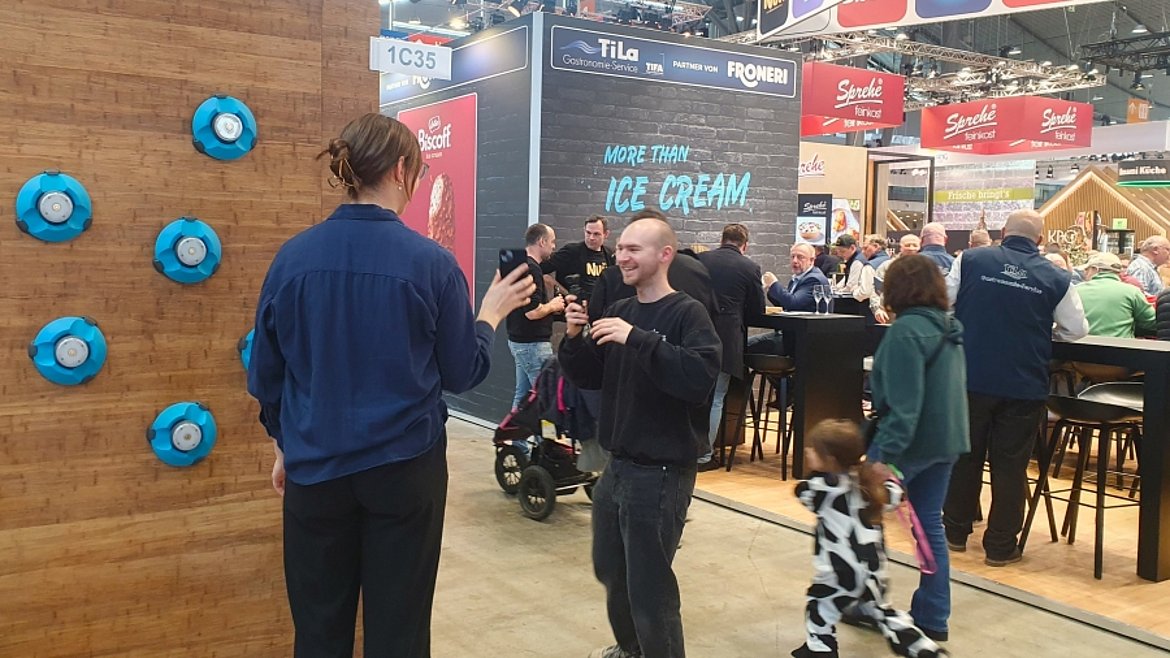 Zwei Personen vor einer Reaktionswand auf einem Messestand