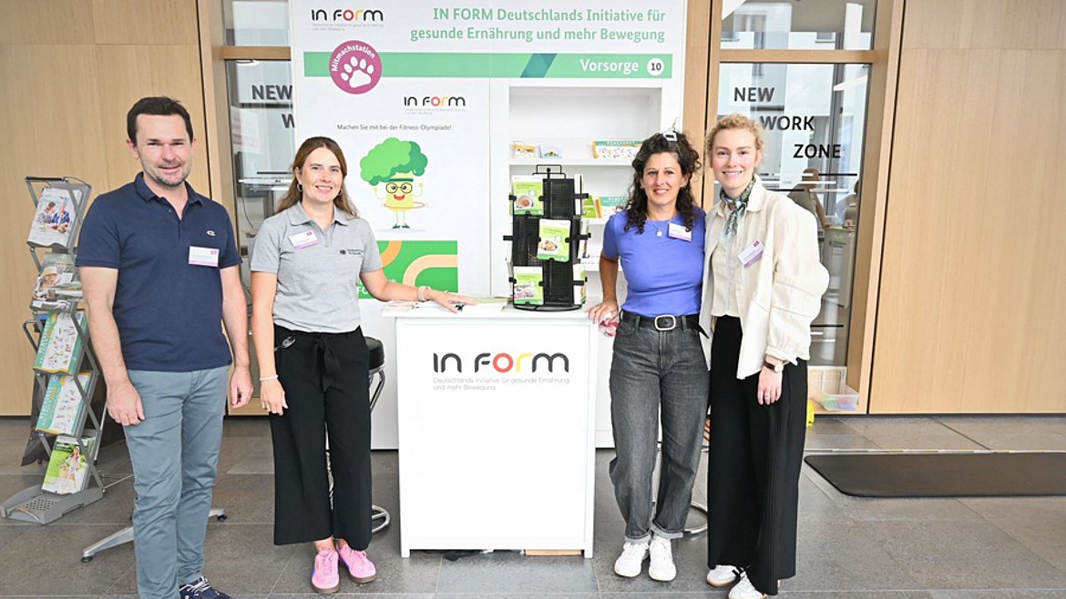 Drei Frauen und ein Mann neben einem Messestand von IN FORM