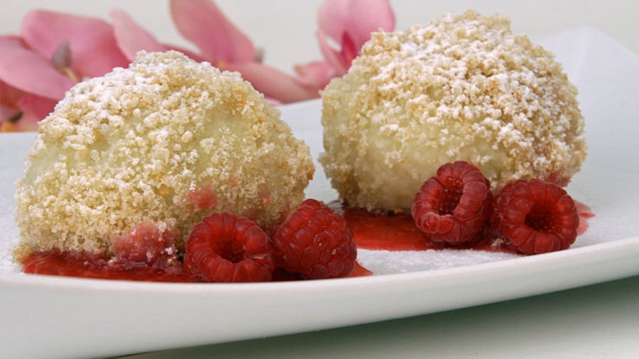 2 gefüllte Knödel mit frischen Himbeeren serviert.