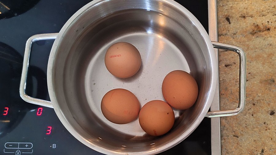 4 Eier in einem kleinen Topf.