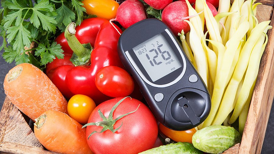 Korb mit Obst und Gemüse, dazwischen Blutdurckmessgerät