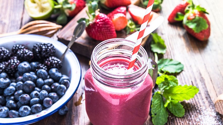 1 Glas Brombeer-Kefir-Mix mit Strohhlam und Beerenobst garniert.