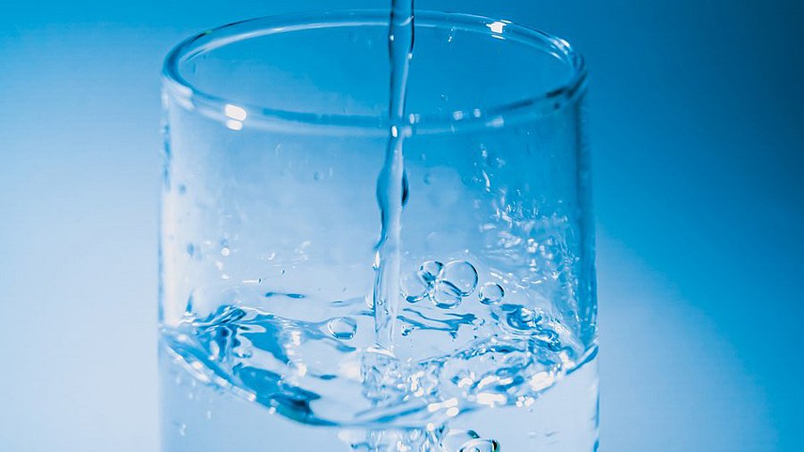 Glas mit Wasser vor blauem Hintergrund