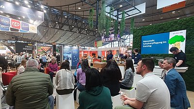 Messegäste auf dem Stand hören dem Talk zu