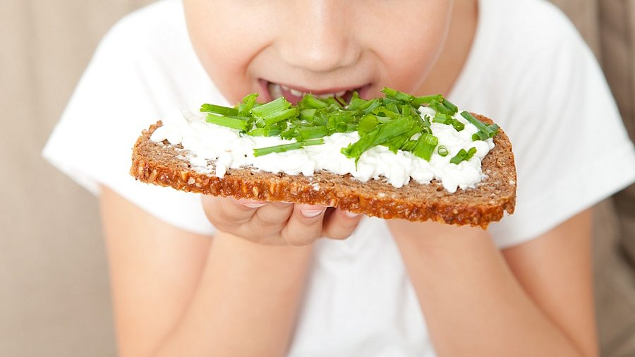 Kind isst ein Brot mit Frischkäse