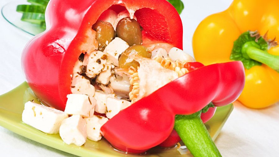 1 rote Paprika, gefüllt mit Feta und Oliven auf weißem Hintergrund.