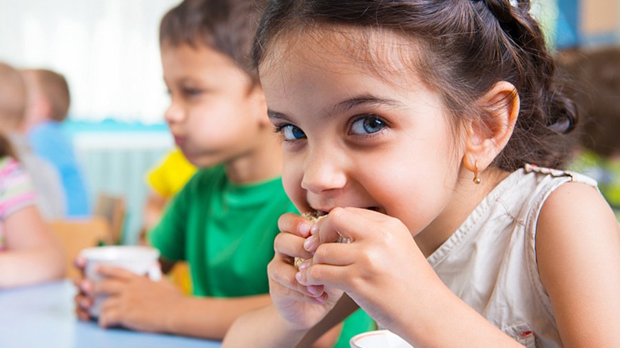 Kindergartenkind isst ein Vollkornbrötchen