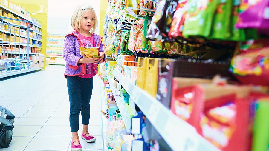 Kleines Mädchen vor einem Süßigkeiten-Regal in einem Supermarkt