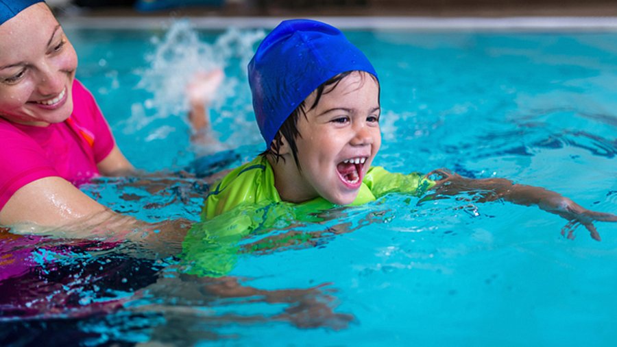 Kleines Kind im Schwimmbecken mit Schwimmlehrerin