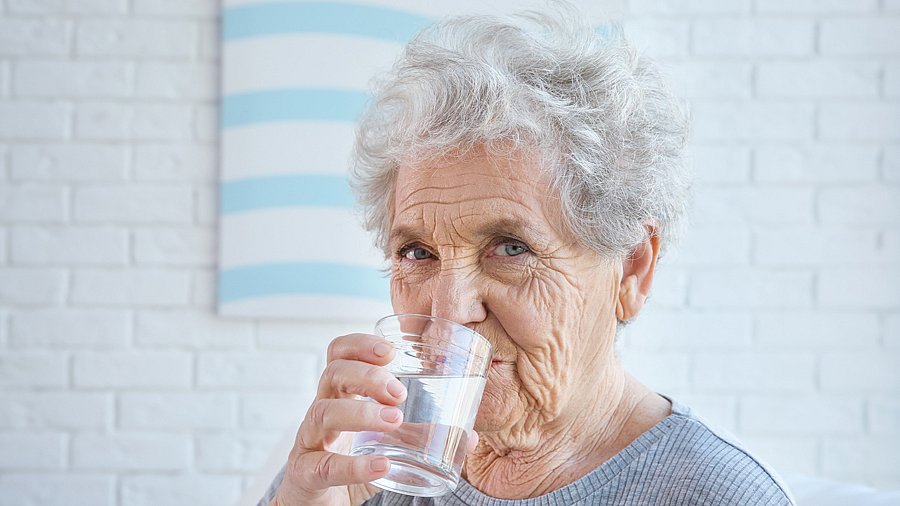 Seniorin trinkt ein Glas Wasser