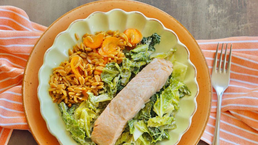 Eine Portion Lachs auf Rahmwirsing, serviert mit Linsenreis.