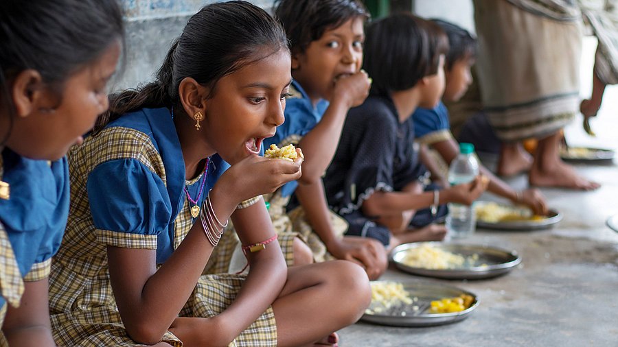 Kinder in Schuluniformen essen zu Mittag (Indien)
