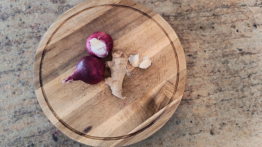 Zwiebel, Knoblauch und Ingwer auf einem Holzbrett.