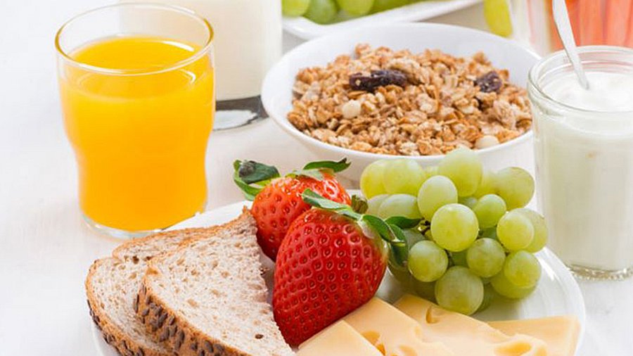 Frühstückstisch mit Orangensaft, Müsli und Früchten