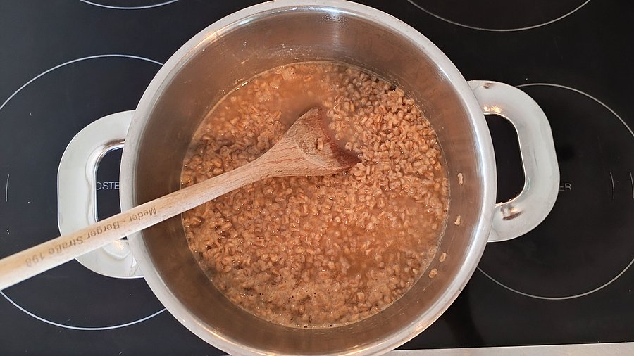 Dinkelreis garen in einm hohen Topf.