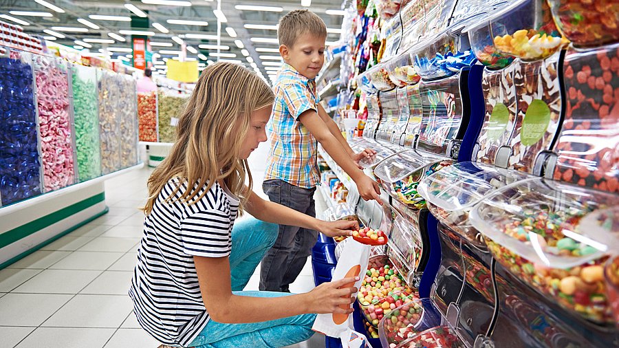Zwei Kinder vor einem Regal mit Süßigkeiten zum Selbstabfüllen