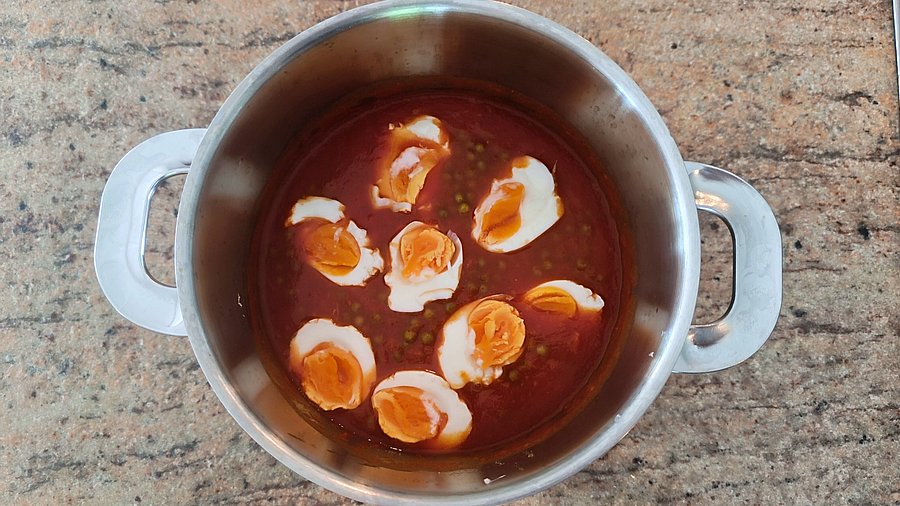 Eier und Erbsen und passierte Tomaten in einem Topf.